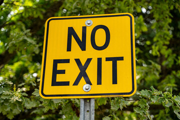 View of yellow no exit sign in outdoor setting.