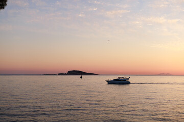 A yacht glides across pastel-colored sea at dusk. Gentle tones and open space express calm, travel, and maritime freedom.