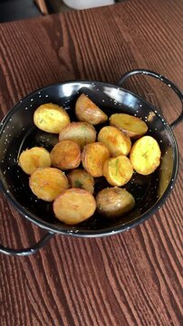 baked young potatoes on a black iron bowl baking tray spinning around its axis