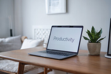 Fototapeta premium A minimalist home office setup with a silver laptop on a light wooden desk. The laptop screen displays the text 