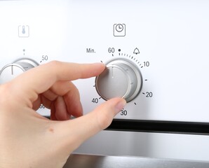 Maximum concept. Woman turning on oven, closeup