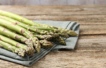 Fresh raw asparagus spears on wooden table, closeup. Space for text