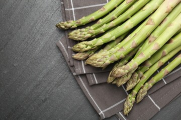 Fresh raw asparagus spears on black table, top view. Space for text