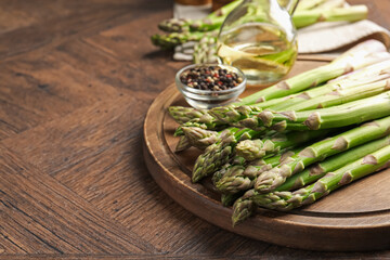 Fresh raw asparagus on wooden table, closeup. Space for text