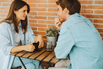 Happy friends talking at table indoors – Laughing man and woman bonding, sharing ideas, future plans, jokes and trust in cozy home or café environment with natural light