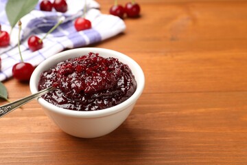 Tasty cherry jam and fresh fruits on wooden table, closeup. Space for text