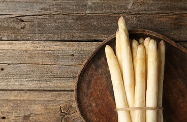 Bunch of raw white asparagus spears on wooden table, top view. Space for text