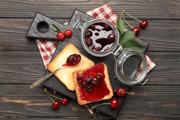 Toasts with tasty cherry jam and fresh fruits on black wooden table, flat lay