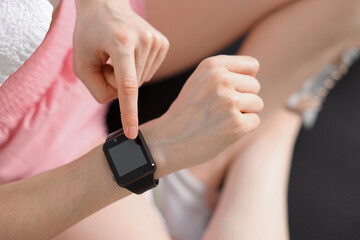 Woman checking fitness tracker during training indoors, closeup