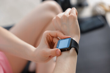 Woman checking fitness tracker during training indoors, closeup