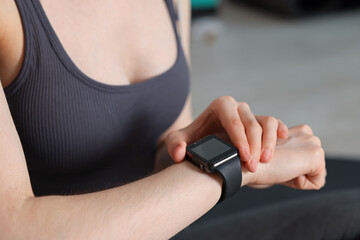 Woman checking fitness tracker during training indoors, closeup