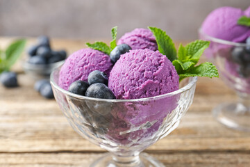 Tasty sorbet with blueberries and mint in dessert bowl on wooden table against grey background,...
