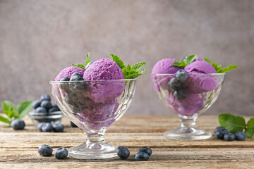 Tasty sorbet with blueberries and mint in dessert bowls on wooden table against grey background,...