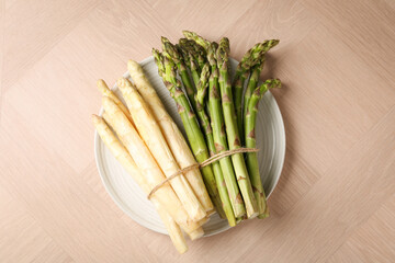 Different raw asparagus spears on wooden table, top view
