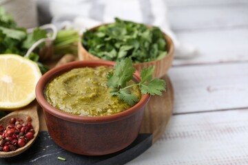 Tasty sauce with cilantro and other ingredients on white wooden table, closeup. Space for text