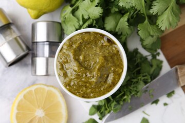 Tasty sauce with cilantro and other ingredients on white marble table, flat lay