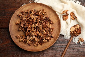 Dried chanterelle mushrooms and spoon on wooden table, flat lay