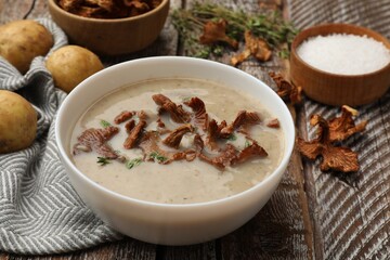 Tasty cream soup with mushrooms and thyme in bowl on color wooden table, closeup