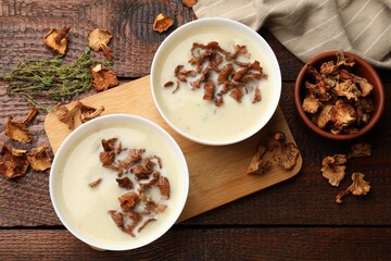 Tasty cream soup, thyme and dry chanterelle mushrooms on wooden table, flat lay