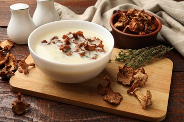 Tasty cream soup with mushrooms and thyme in bowl on wooden table, closeup