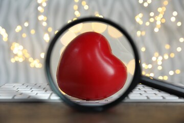 Decorative heart, computer keyboard and magnifying glass against blurred lights, bokeh effect....