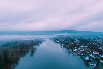Fototapeta premium Aerial View of Flooded Town with Submerged Roads and Rooftops Under Rolling Fog