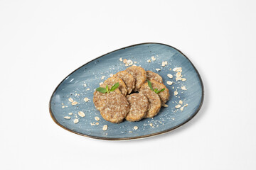 Sugar-free oatmeal cookies garnished with fresh herbs and oat flakes, served on a plate against a white background