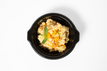 Millet porridge with milk and pumpkin, served on a plate against a white background