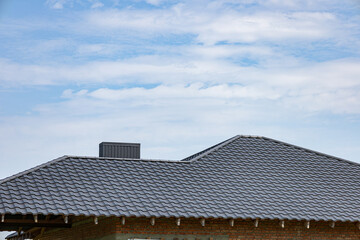 Fototapeta premium Metallic tiled rooftop showcases durable roofing materials under a clear blue sky, highlighting craftsmanship in construction
