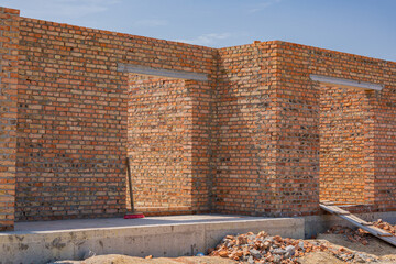 Brick walls are being constructed as part of a new building project under clear skies and bright...