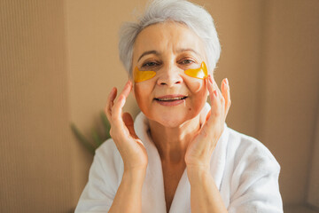 Eye patch beauty aging treatment. Mature adult old woman with under eye collagen pads. Senior woman...
