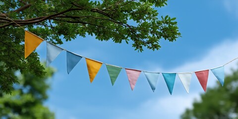 Colorful pennant flags hanging from tree against blue sky