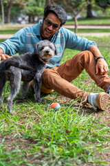Man petting his mixed breed dog in park with colorful ball