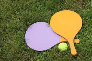 Beach tennis paddles and ball on grass. Active lifestyle, games and sports. Tennis set for the open...