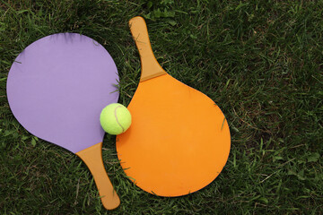 Beach tennis paddles and ball on grass. Active lifestyle, games and sports. Tennis set for the open...