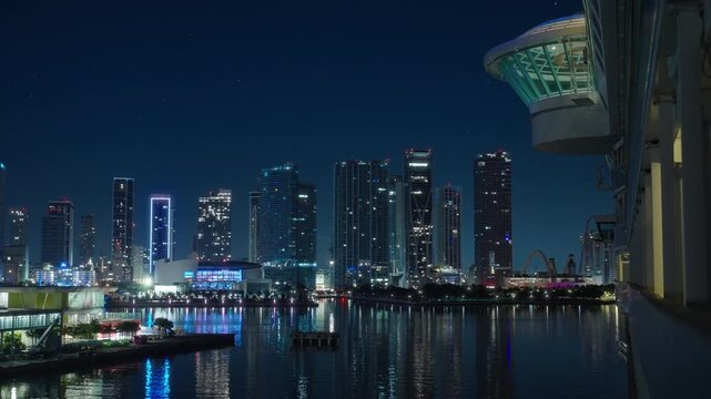 A breathtaking and stunning nighttime view from a cruise ship as it approaches the bustling port of Miami, showcasing the citys vibrant skyline and beautiful reflections shimmering on the water