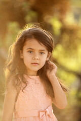 Portrait of a child girl  standing in nature  and looking at camera at sunset time