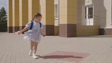 Little child with school backpack having fun spin in school yard, happy dreamy kid, first grader...
