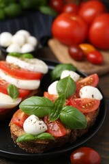Tasty sandwiches with mozzarella cheese, tomatoes, basil and spices on wooden table, closeup