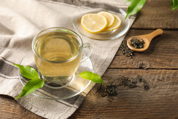 Refreshing green tea with lemon and leaves on wooden table, closeup