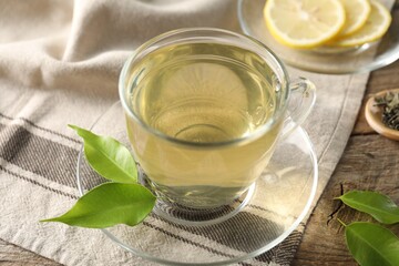 Refreshing green tea with lemon and leaves on wooden table, closeup