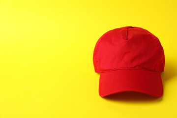 Red baseball hat on yellow background, space for text