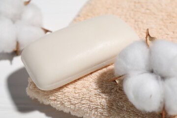Soap bar, cotton flowers and towel on white table, closeup