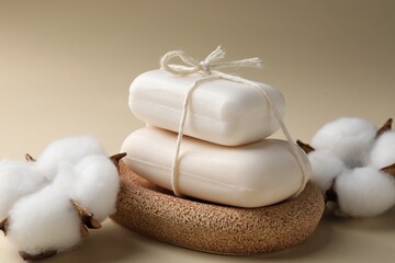 Soap bars and cotton flowers on dark beige background, closeup