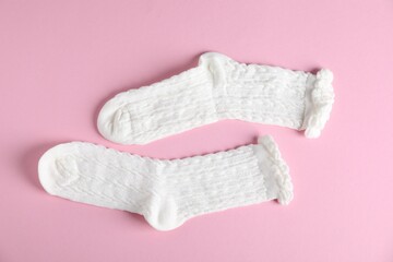 Pair of comfortable white socks on pink background, top view