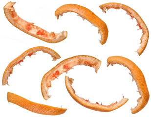 Several curved strips of grapefruit peel with pink pulp remaining, arranged on an isolated background