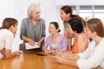Portrait of positive older woman participating adult education class with mixed age group of women,...