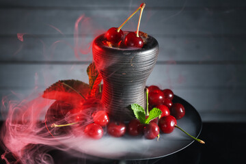 Hookah with cherries and smoke on black background, closeup