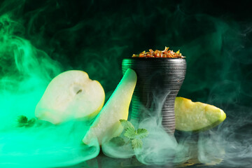 Hookah bowl with pear pieces, mint and smoke on black table, closeup