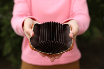 Woman with open empty wallet outdoors, closeup